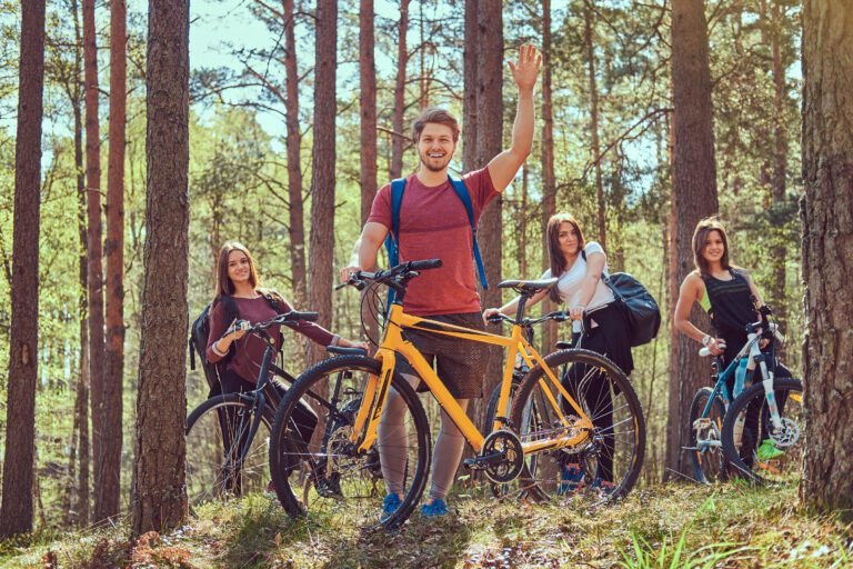 Group of smiling friends standing in the forest with bikes.