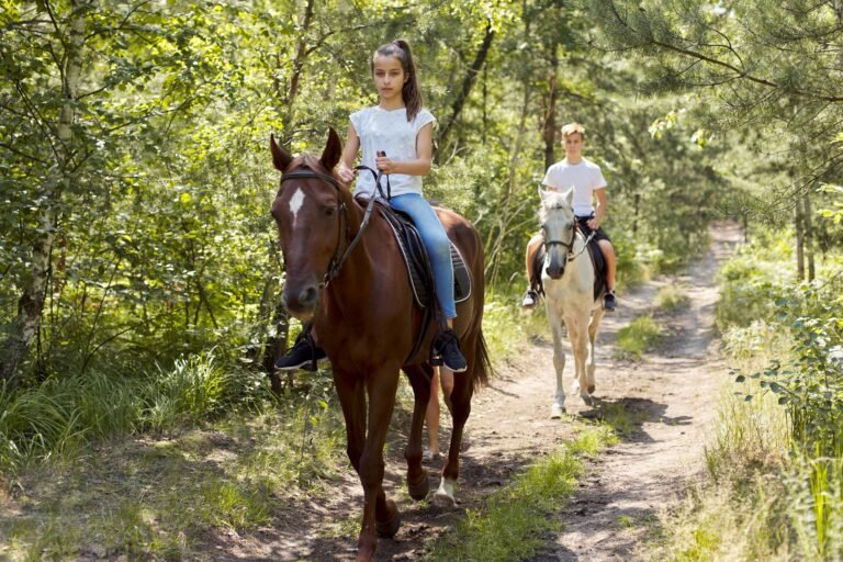 Group of teenagers on horseback riding in summer park.