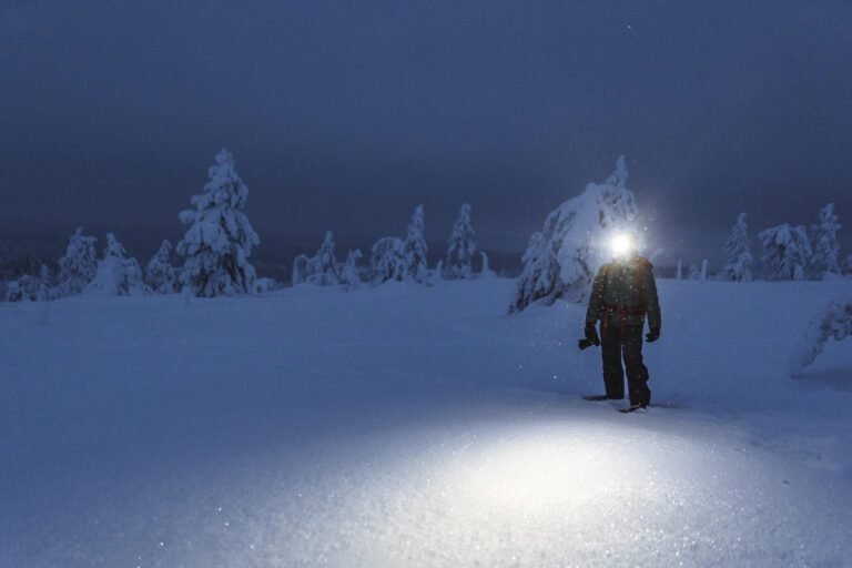 Trekker with a headlamp walking in a snowy Riisitunturi National Park, Finland
